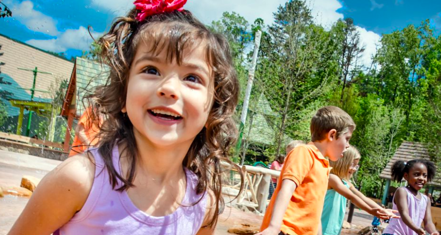 Wildwood Creek at Dollywood play area with children enjoying the pop-jet water features and instruments.